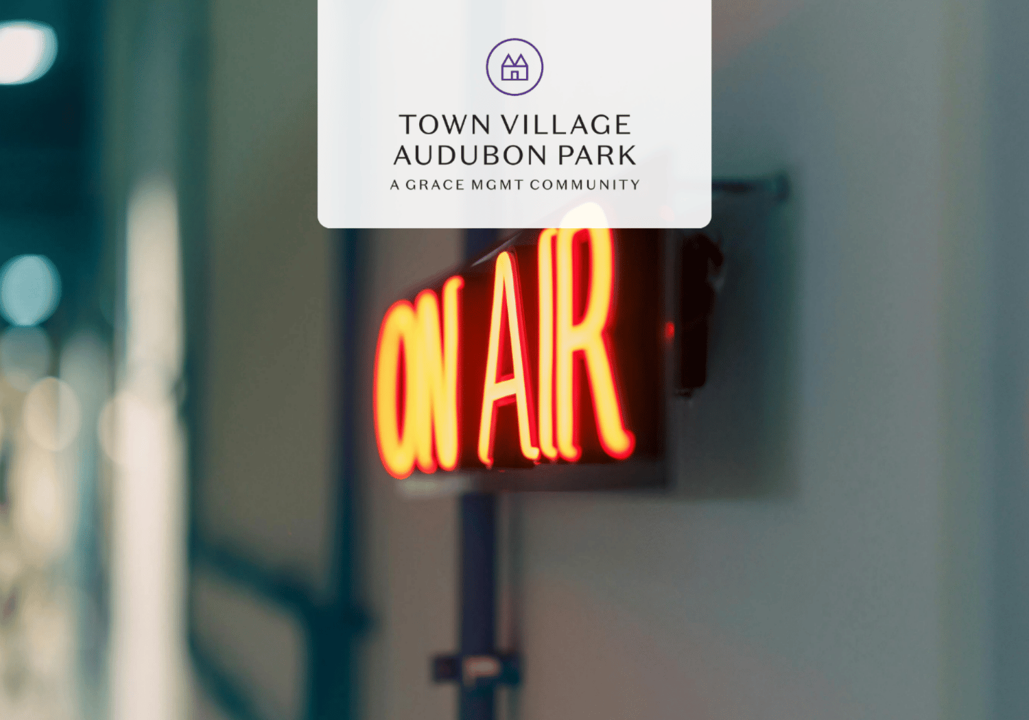 Blurred indoor scene with a red neon 'OPEN' sign and a white branding card reading 'Town Village Audubon Park' hovering above.