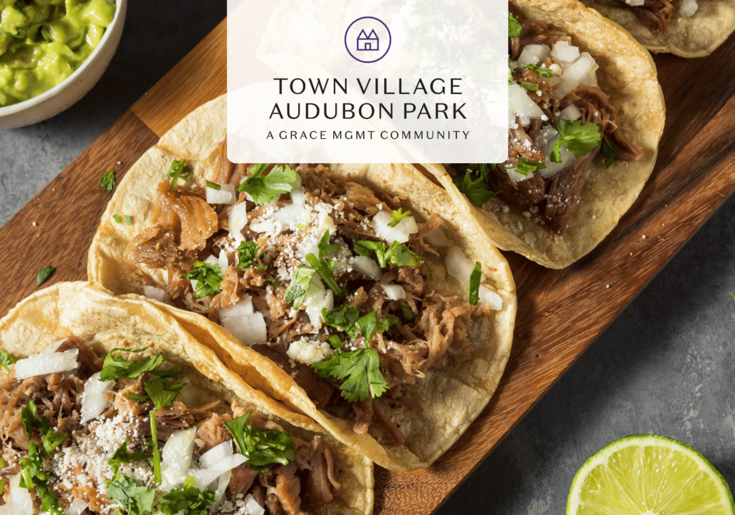 Tacos stuffed with shredded meat, onions, cilantro, and cheese on a wooden board, with lime and guacamole nearby and a Town Village Audubon Park logo overlay.